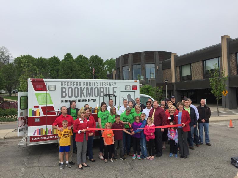 Photo of community members standing in front of bookmobile for ribbon cutting ceremony