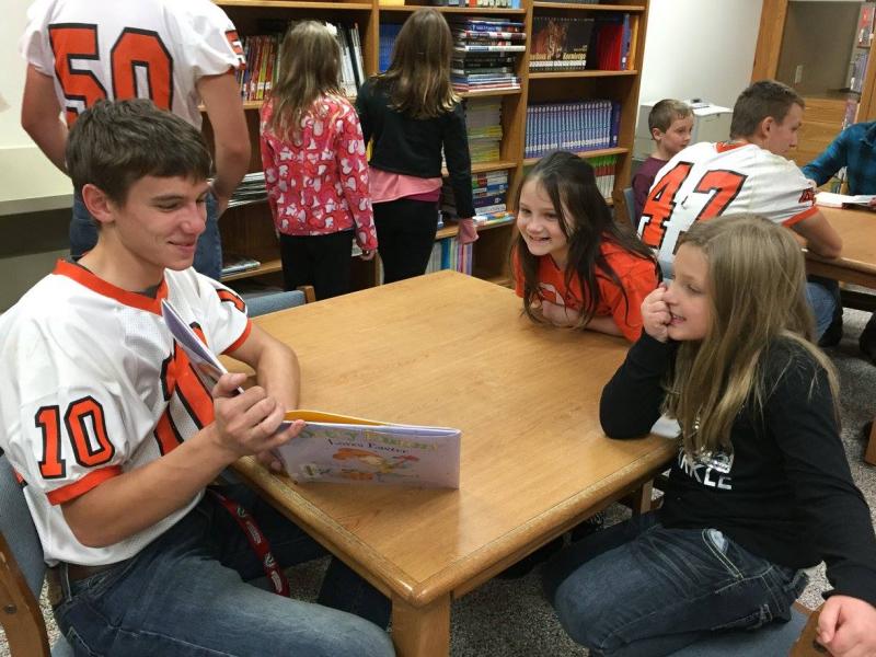 Varsity football player reads to 2 fourth graders