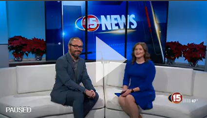 Image of paused video with two people sitting on a couch in a newsstation interview