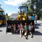 Children and adults sitting in the bucket of a loader truck